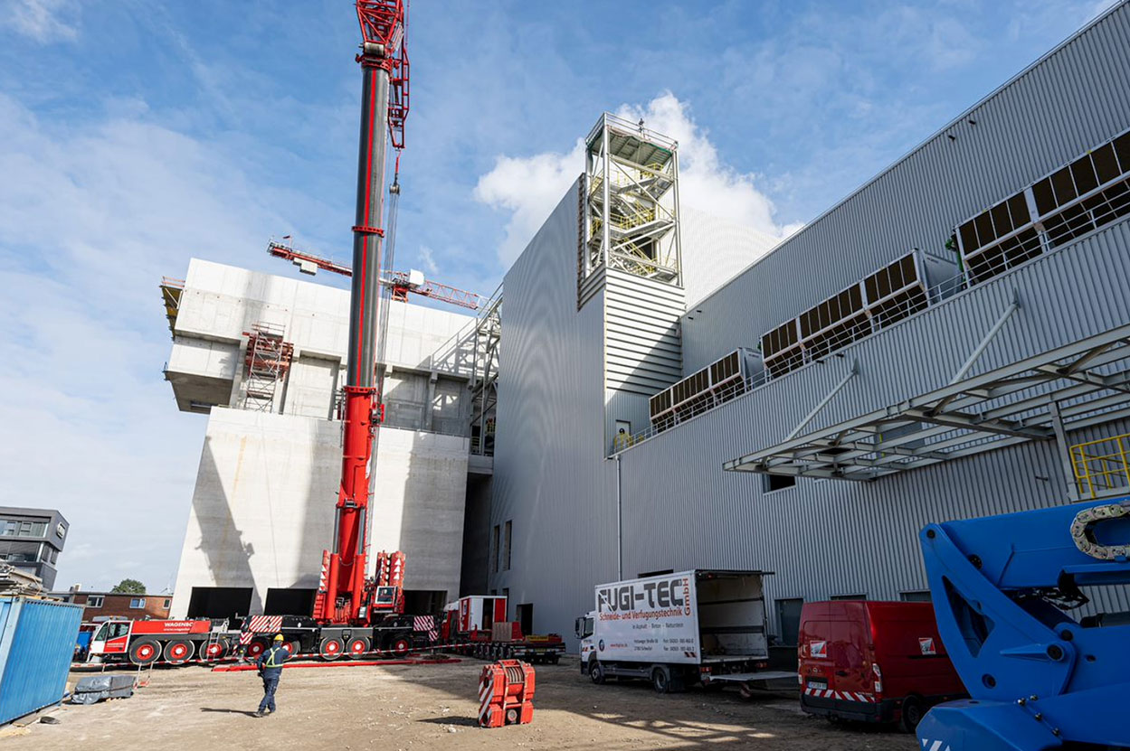 Baustelle in der Außenansicht, große Betonwände mit Kran davor